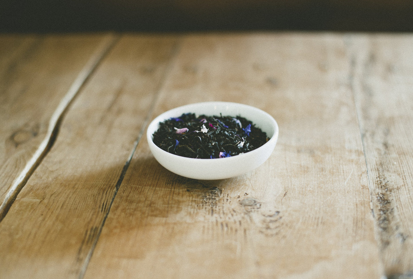 Small white dish filled with Earl Grey on wooden table. 