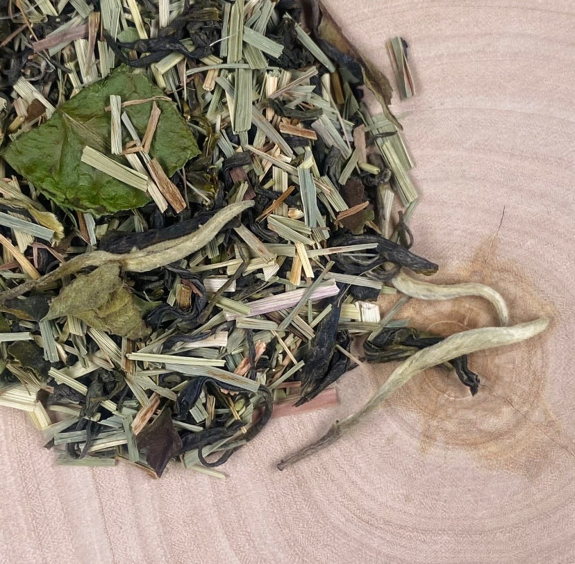 Loose Leaf Organic Orange Blossom Green tea with white tea needles on birch tree slice.
