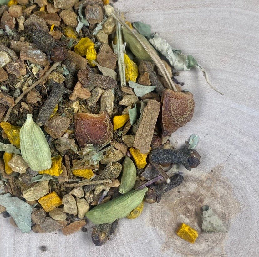 Organic Turmeric Chai tea blend laying on a birch piece of wood.