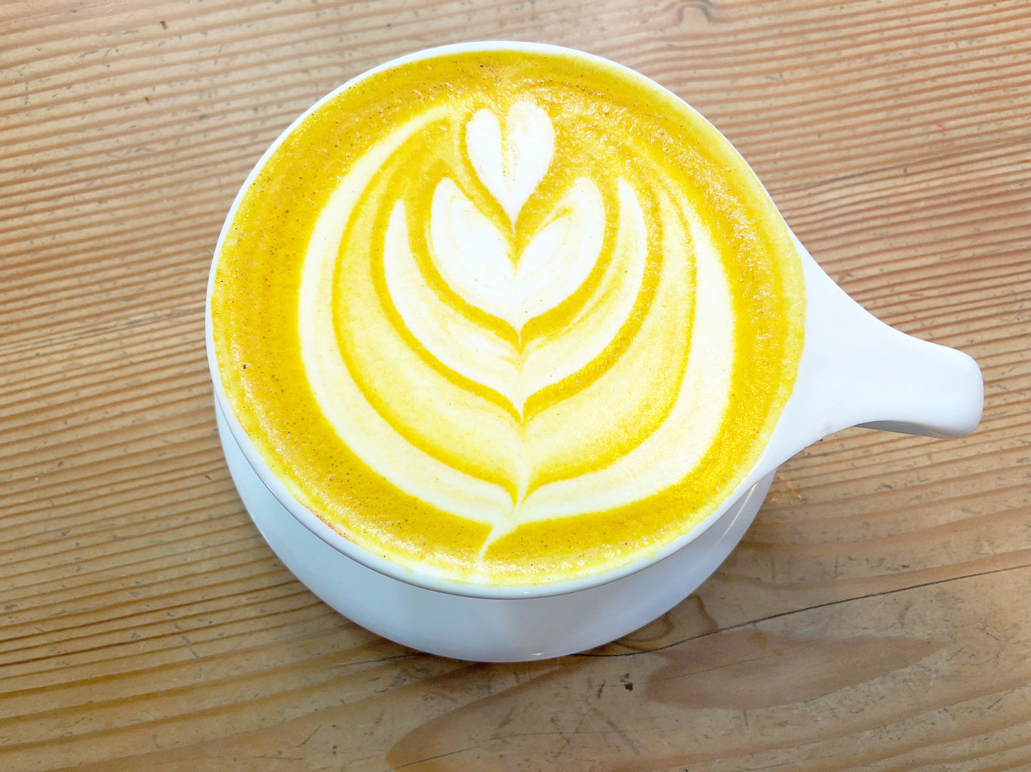 Cup of Organic Turmeric Powder Latte art of a flower.